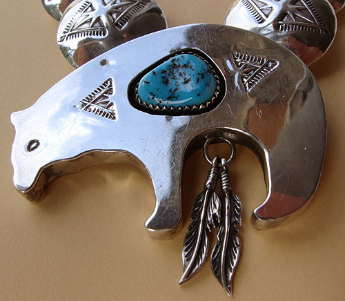 Le pendentif du collier Navajo représente un Ours Fétiche orné d'une turquoise et 2 plumes d'Aigle en argent, c'est un bijou ethnique haut de game