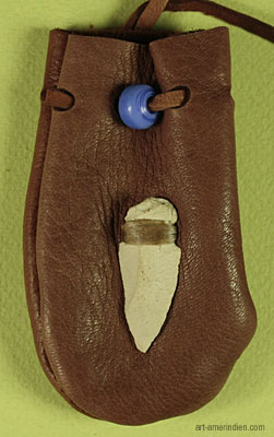 détail de la pointe de flèche en pierre taillée et de la perle de verre bleu ornant ce médicine bag amérindien en cuir